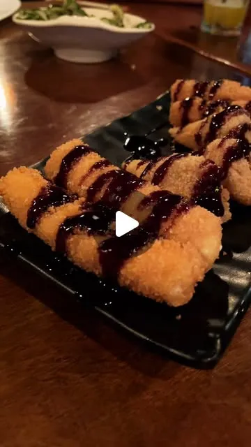 Hot rolls empanados com molho tarê em prato preto
