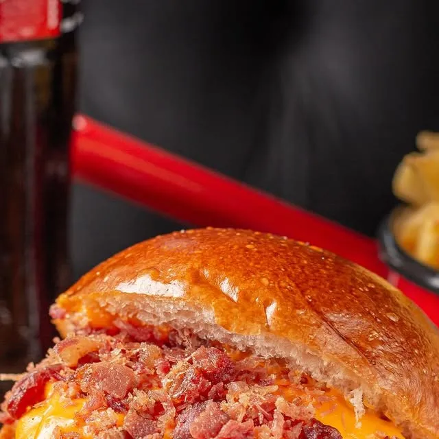 Burger transbordando cheddar e bacon, em tábua