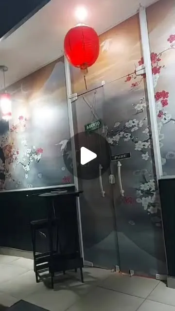 Entrada com porta de vidro, painel de flores de cerejeira e lanternas vermelhas